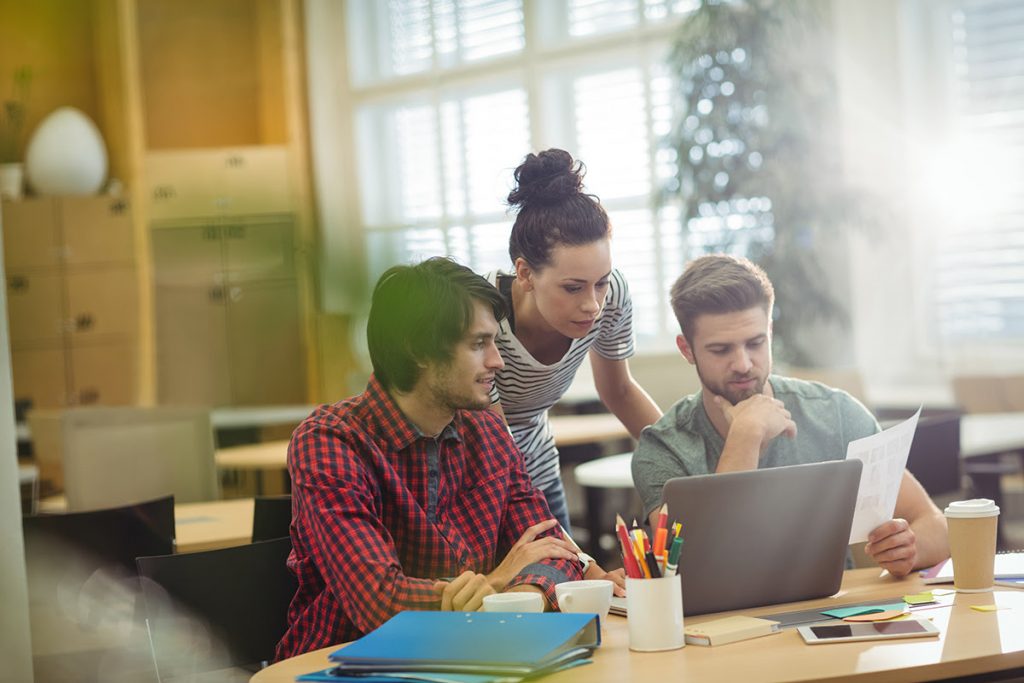 Group of business executives discussing over laptop at their desk in the office